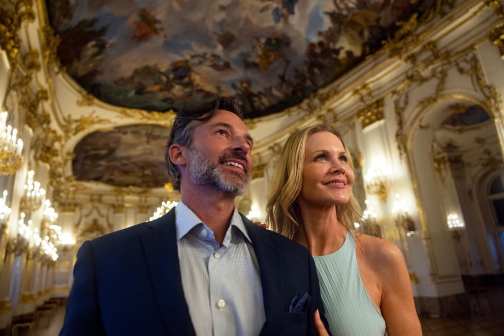 An elegant couple sharing a moment within a radiant, gold-accented foyer.