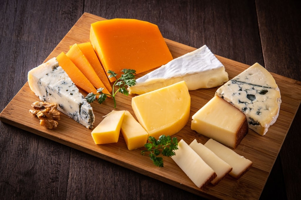 A rustic wooden board showcases a diverse selection of artisanal cheeses.