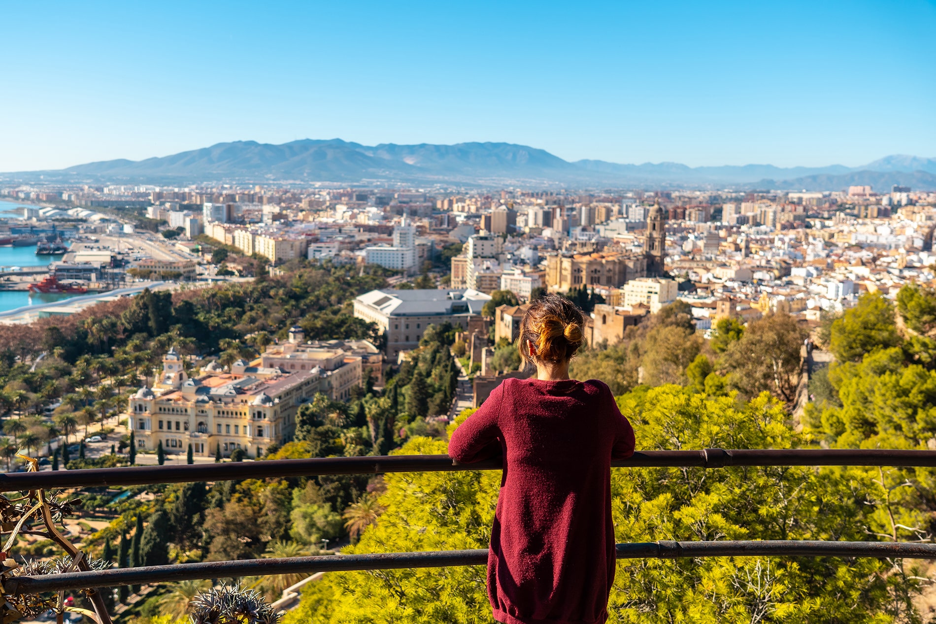 Young woman looking at the views of the city and the Cathedral of the Incarnation of Malaga from the Castillo de Gibralfaro