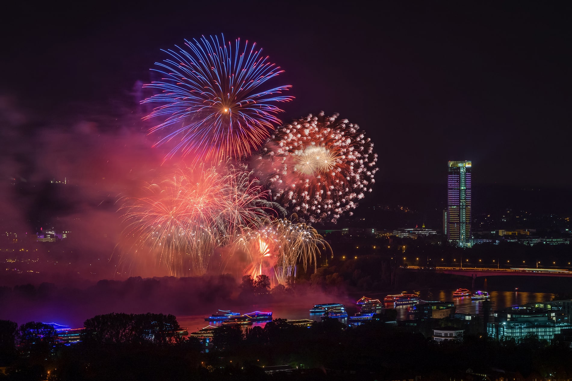 Vibrant fireworks illuminate the night sky over illuminated boats along the Rhine River during the Rhein in Flammen festival in Bonn.