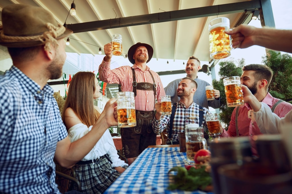 Friends in traditional attire raise beer steins in a festive toast during an Oktoberfest celebration in Germany.