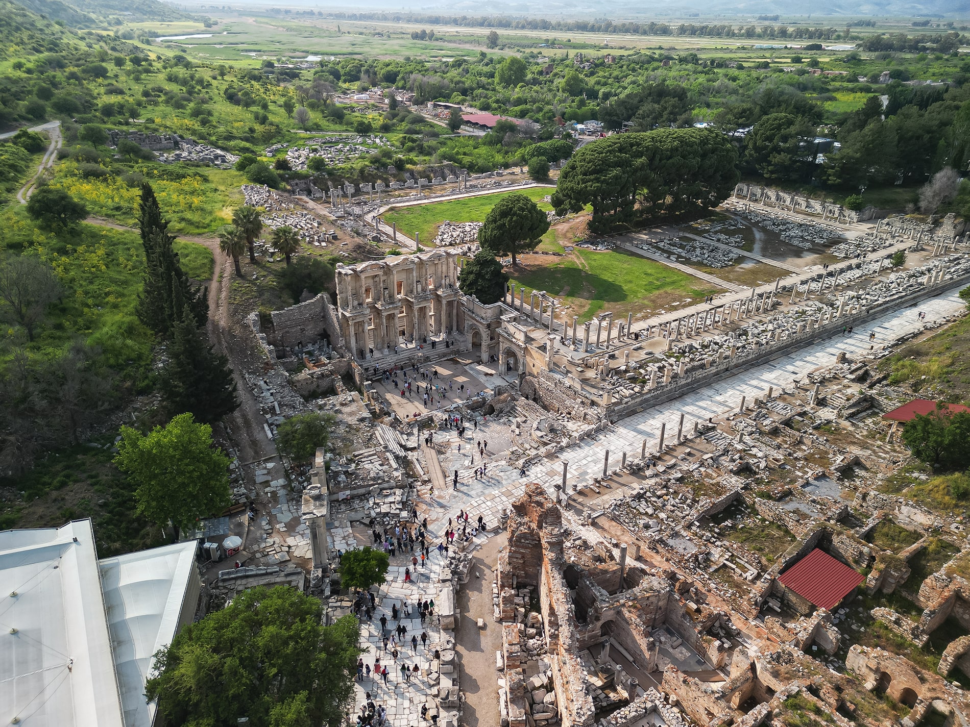 The Library of Celsus in Ephesus stands amid marble lanes, columns, greenery, and Turkey’s historic hills.