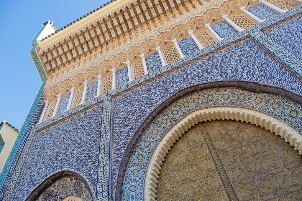 A golden brass entryway at the Royal Palace in Fez is framed by elaborate zellij tilework.