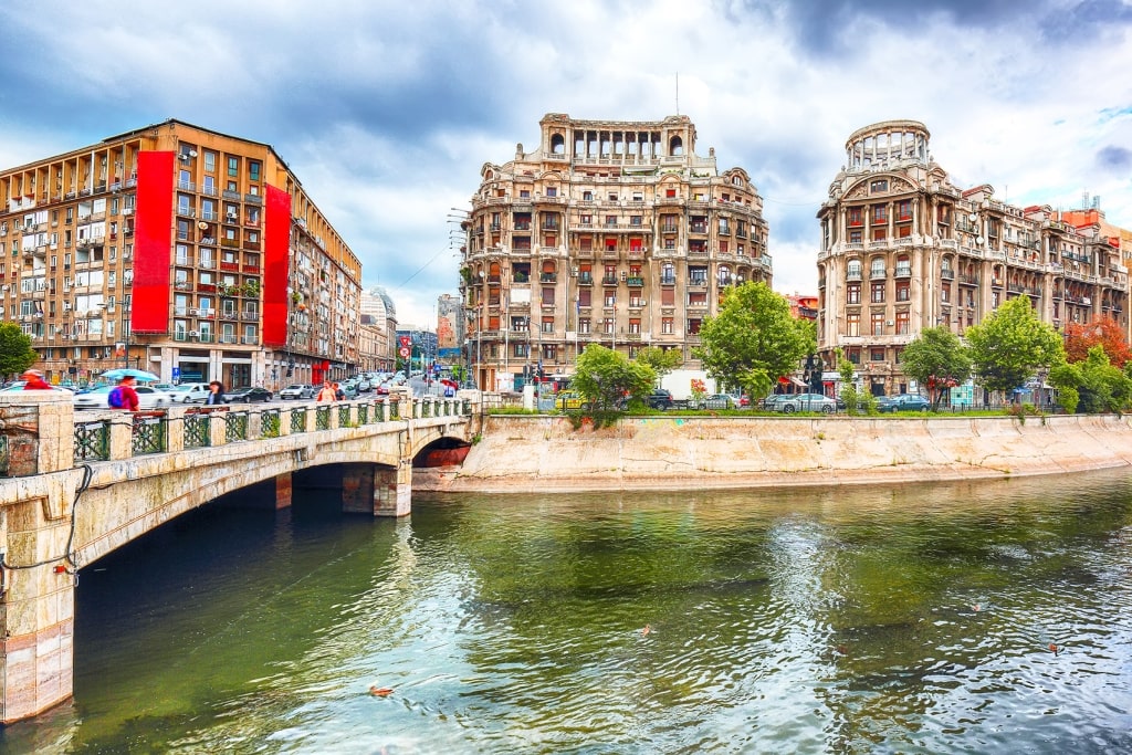 Grand historic buildings line the Dâmbovița River in Bucharest, Romania.