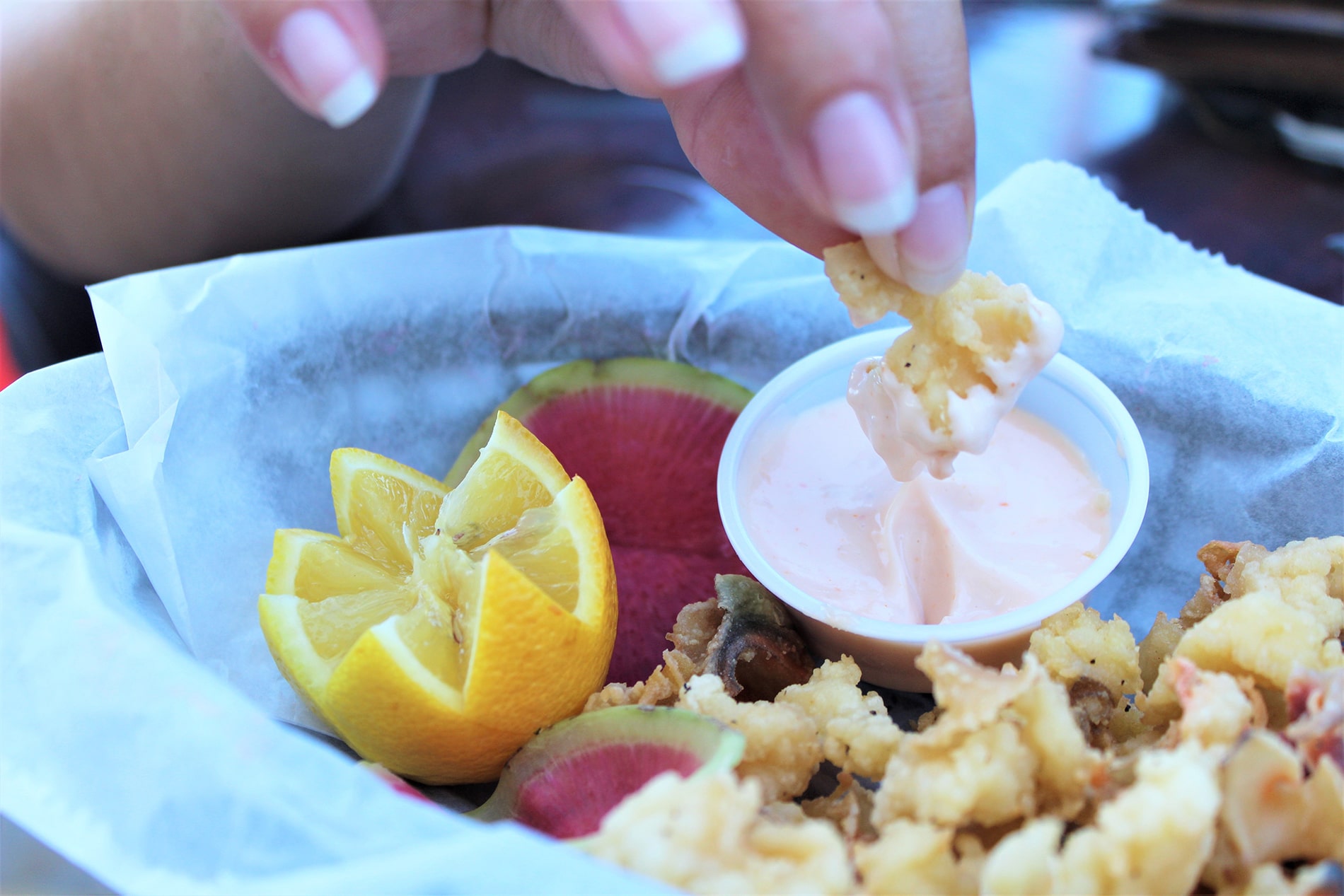 Dipping a piece of golden cracked conch into creamy sauce captures the simple, hands-on indulgence of enjoying fresh island seafood on shore
