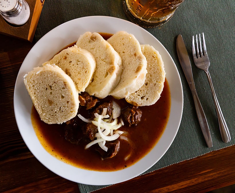Savory Czech beef stew accompanied by classic steamed bread dumplings.