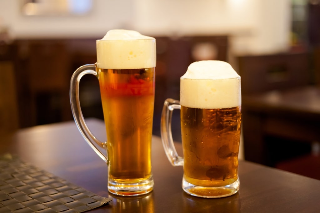 A golden Czech beer crowned with thick foam sits ready on a wooden table inside a traditional Czech tavern.