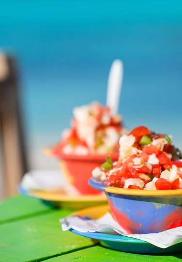 Two bowls of Bahamian conch salad and bottle of beer