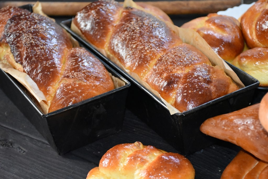 Golden, freshly baked cozonac sweet braided bread in traditional loaf pans.