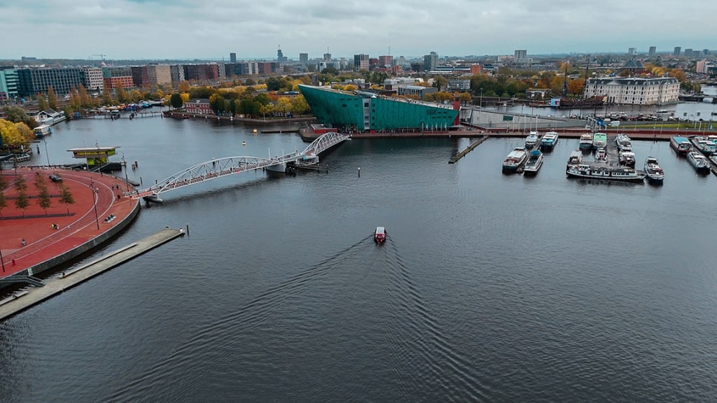 Aerial drone view NEMO museum in Amsterdam autumn cityscape narrow old houses, canals, boats bird's eye view.