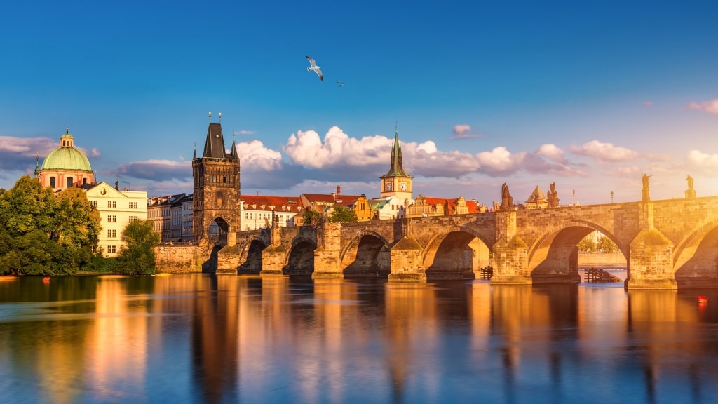 The historic Charles Bridge stretches across the calm Vltava River in Prague.