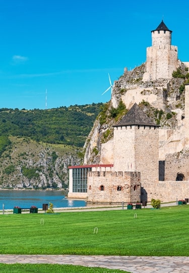 Medieval towers of Golubac Fortress overlook lush hills along the Danube.
