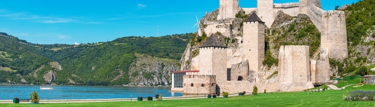 Medieval towers of Golubac Fortress overlook lush hills along the Danube.