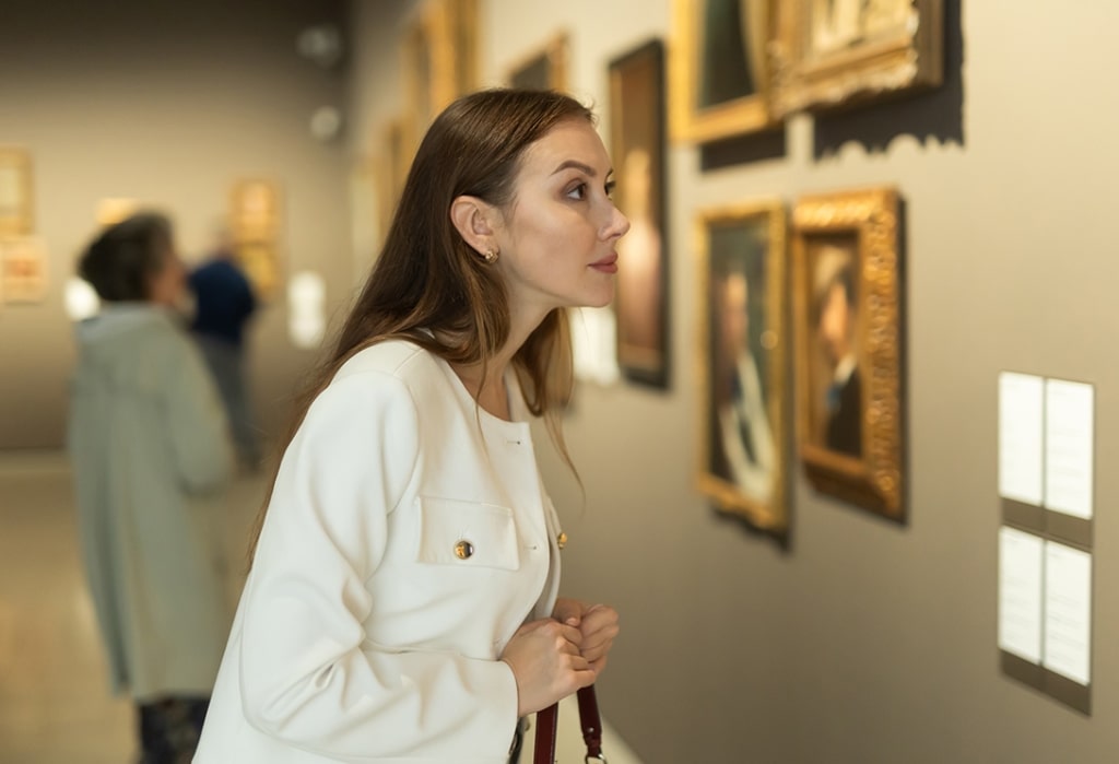 Leaning in to study a gilded portrait, a museumgoer embodies the intimate, reflective pace of shore excursions designed for cultural discovery.