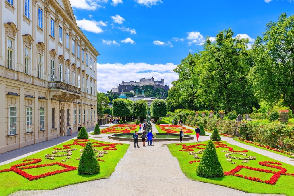 Mirabell Palace and Gardens in the summer surrounded by lush greenery.
