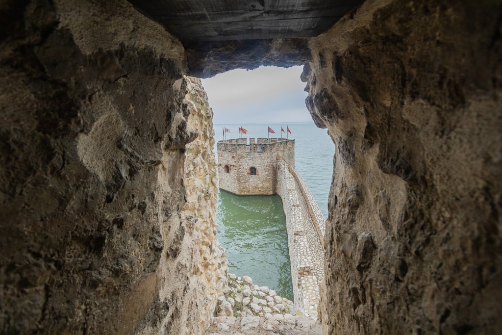 Weathered stone architecture offers a framed perspective of a medieval tower standing guard over the Danube.