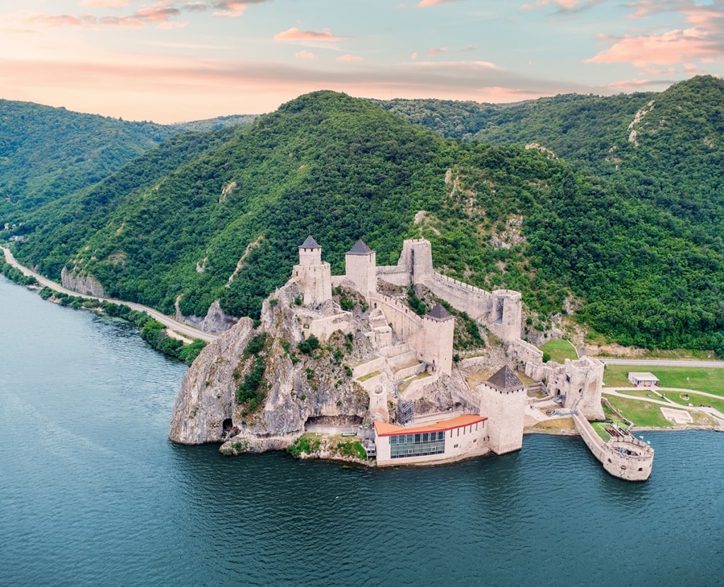 Golubac Fortress sits on rocky cliffs overlooking the Danube and green hills.