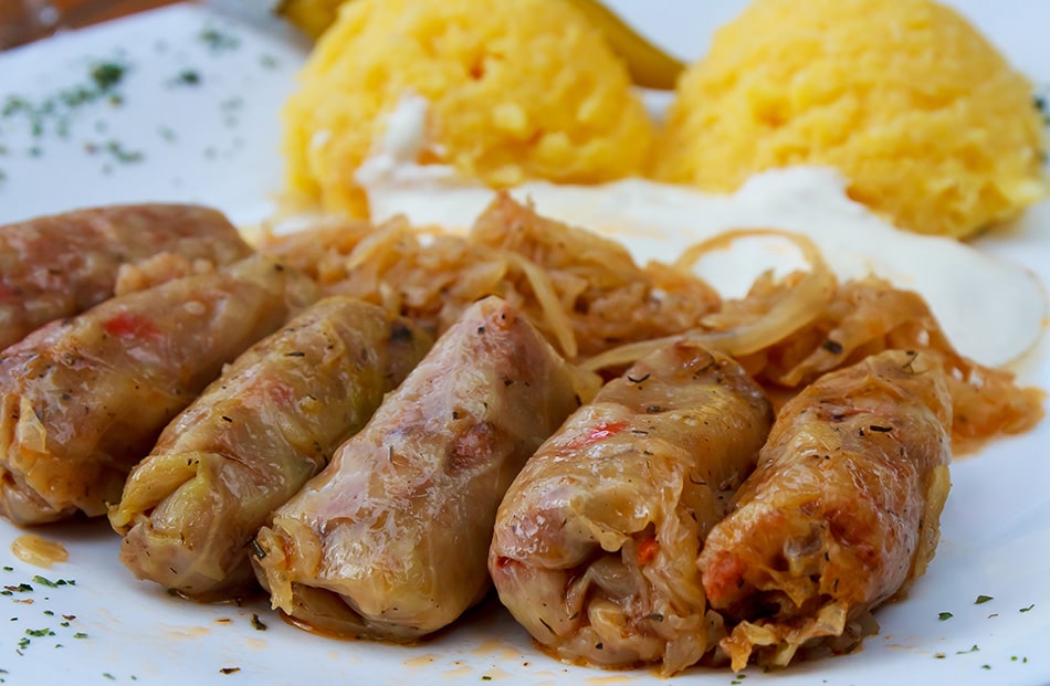 A plate featuring mămăligă and sarmale—pickled cabbage rolls served with a side of hearty polenta.