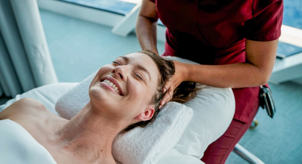 A guest enjoys a relaxing head massage during a soothing spa treatment aboard the Celebrity Solstice.