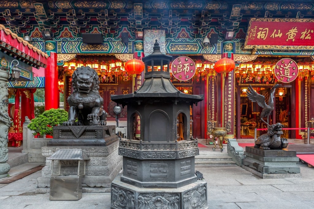 Intricate traditional architecture, bronze guardian statues, and incense burners at the historic Sik Sik Yuen Wong Tai Sin Temple in Hong Kong