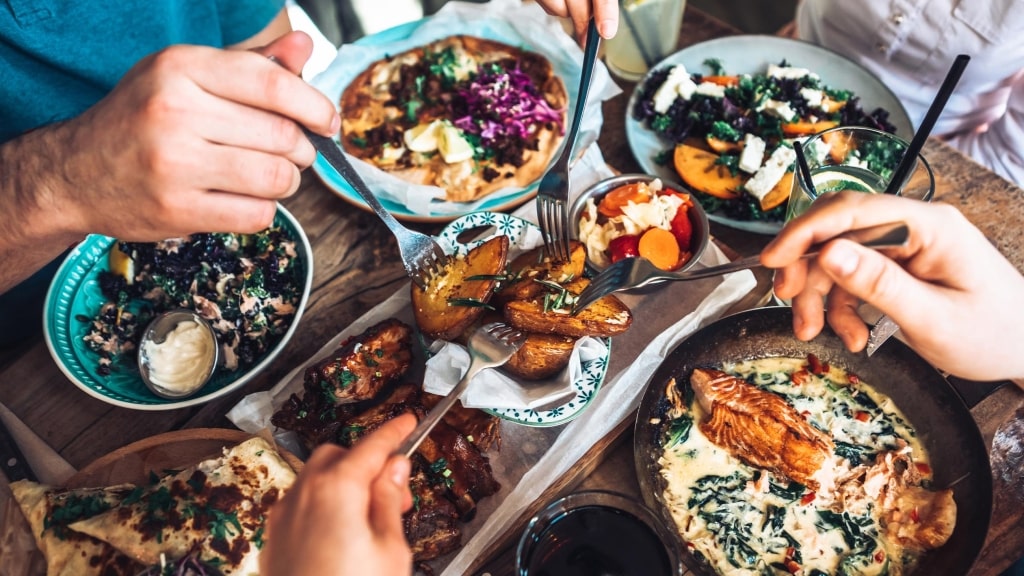 Friends gather around a rustic table to share a vibrant meal.