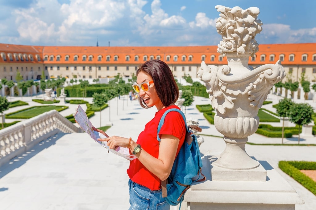 Happy young tourist reading a map and admiring an amazing view of a flower garden in Bratislava, Slovakia
