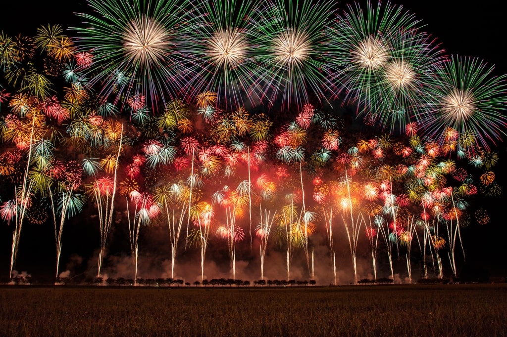 A spectacular wide burst of colorful pyrotechnics fills the night sky over the Omono River during the prestigious Omagari Fireworks Festival.