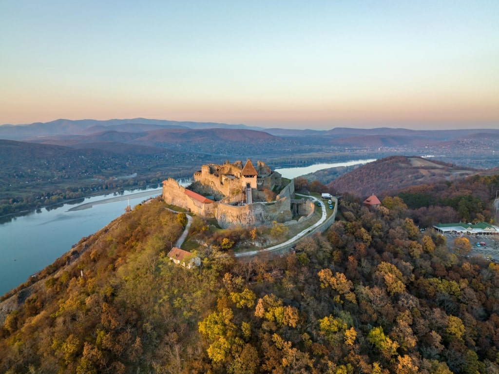 Aerial panoramic drone view of the beautiful high castle of Visegrad on a moody autumn sunset. Danube Bend (Dunakanyar) and an amazing golden sunset in the background.
