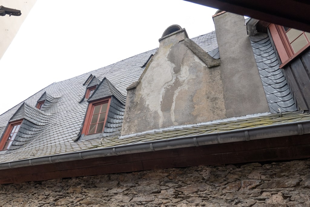 A detailed view of the slate tile roof, gables, and dormer windows of the historic Marksburg Castle complex.