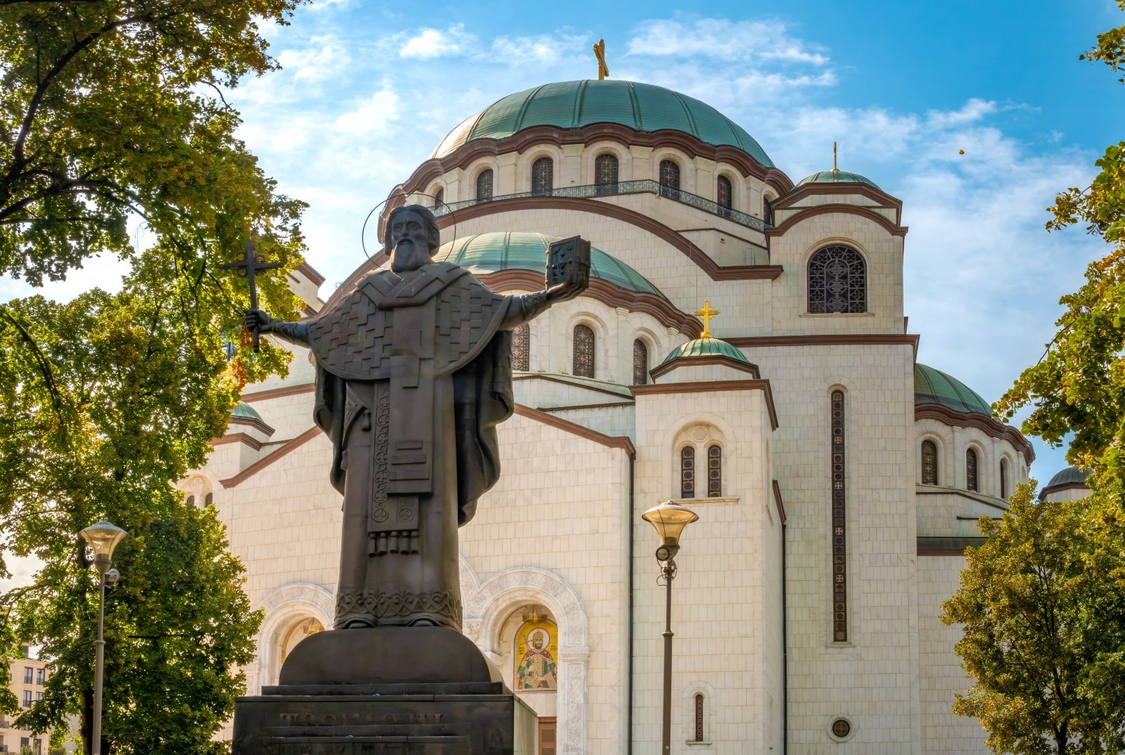 The Church of Saint Sava (Hram Svetog Save) with the bronze statue of Saint Sava standing in the foreground park.