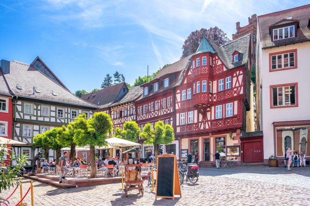 Outdoor cafes and colorful half-timbered buildings in the historic Marktplatz on a sunny afternoon.