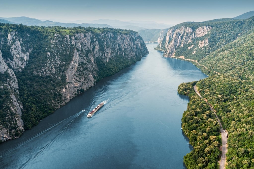 Aerial view of a cruise ship traveling through the Danube River's Iron Gate between Serbia and Romania.