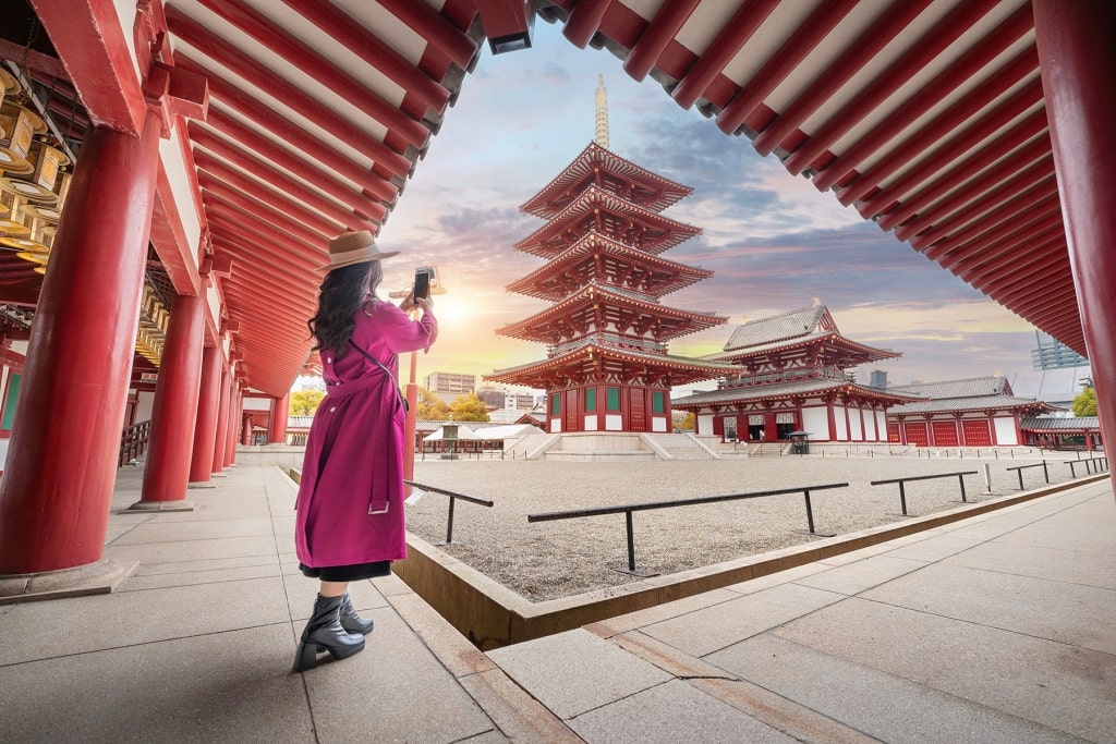 A traveler takes a photo of the iconic five-story pagoda and inner complex of Shitennoji Temple, one of Japan's oldest Buddhist temples in Osaka.