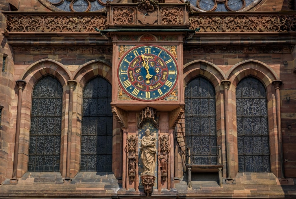 Ancient astronomical clock with Roman numerals and planet symbols displaying days of the week on the facade of Strasbourg Cathedral.