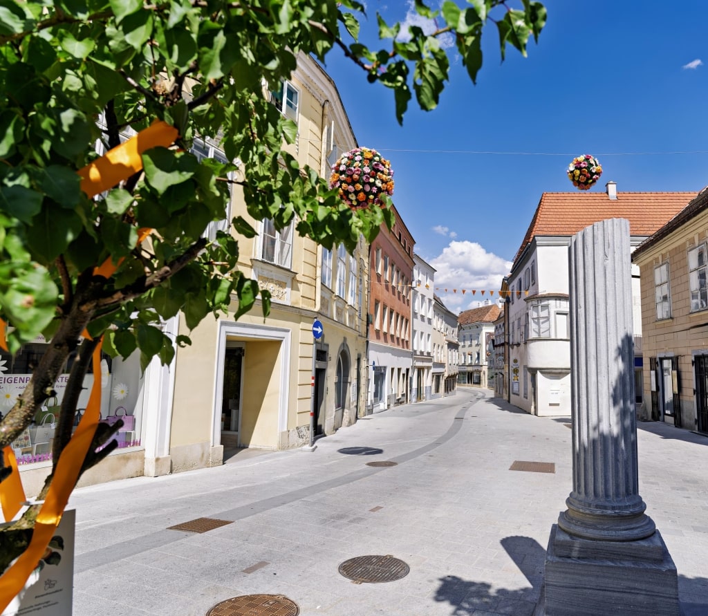 Decorative floral ornaments float above a sunny, historic street in the heart of Old Town Krems.
