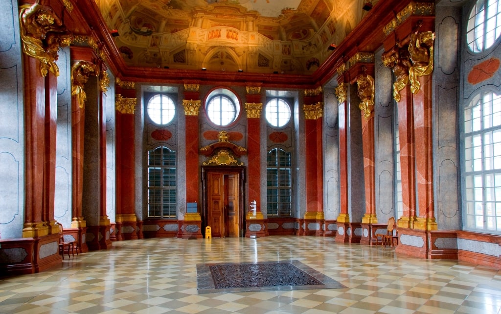 The Marble Hall at Melk Abbey features gold details and majestic red marble columns.