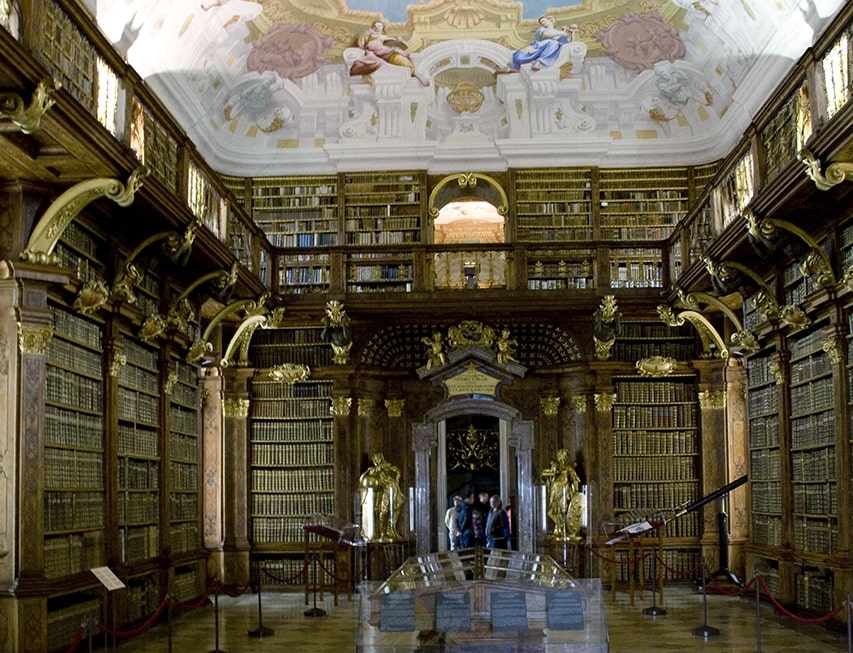 An ornate ceiling fresco crowns the grand, book-lined library of Melk Abbey.