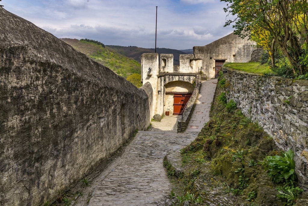 A cobblestone ramp leads through the fortified stone walls and outer gates of Marksburg Castle.